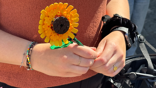 Eine Frau hält eine Blume aus Lego in den Händen