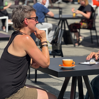 Zwei Frauen sitzen sich gegenüber, zwischen Ihnen steht eine Tasse und Sie Unterhalten sich