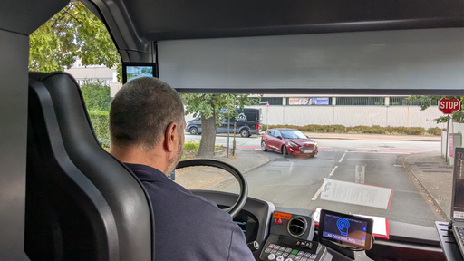 Begleitung eines Busfahrers bei erster Fahrt des autonomen Busses, Sicht vom Innenraum auf die Straße