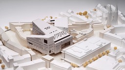 Ein weißes Stadtmodell mit einem markanten Bau in der Mitte