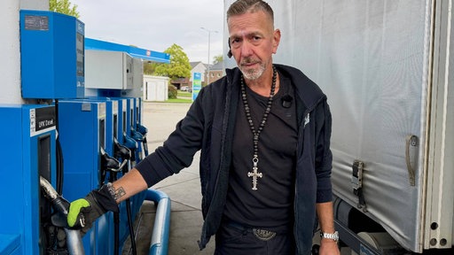 Ein Mann steht an der Zapfsäule einer Tankstelle