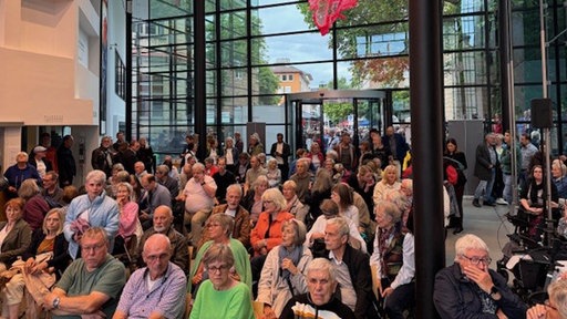 Das Publikum in einem voll besetzten Saal, einige Menschen stehen, 
