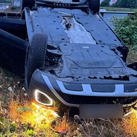 Das Bild zeigt ein Auto auf dem Dach nahe des Flussufers liegend.