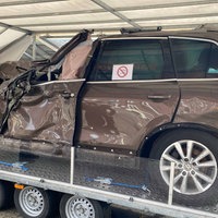 Ein Autowrack welches Vorne eingedrückt ist , steht auf einer Art Podest in einem Zelt