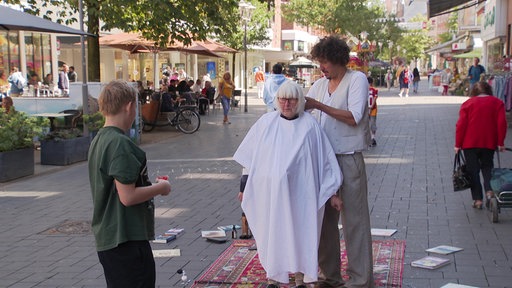 Danny Beuerbach schneidet Birgit Niedrich die Haare in der Stadt.