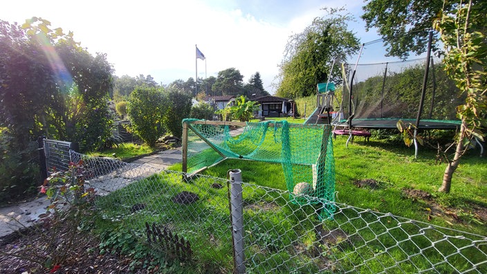 Ein Kleingarten mit Fußballtor und Trampolin im Vordergrund