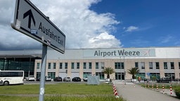 Auf dem Foto ist ein Backsteingebäude mit einem Schild, auf dem "Airport Weeze" steht.