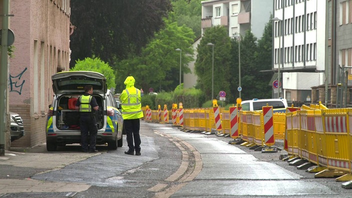 Zwei Polizisten stehen am Heck eines Polizeiautos