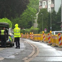Zwei Polizisten stehen am Heck eines Polizeiautos