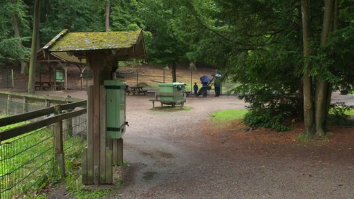 Leeres Wildgehege mit drei Besuchern 