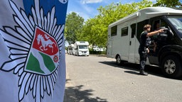 Das Bild zeigt einen Polizisten an einem Wohnwagen. 