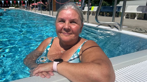 Eine Frau lehnt auf dem Beckenrand in einem Freibad