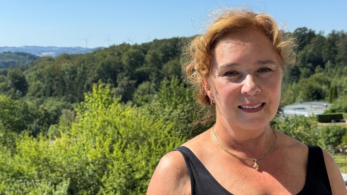 Eine Frau, im Hintergrund ein Wald