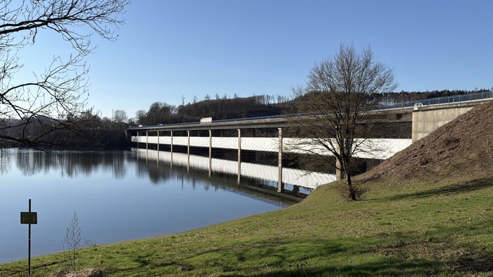 Eine Brücke, die über einen See führt und wegen Bauarbeiten eingehüllt ist.