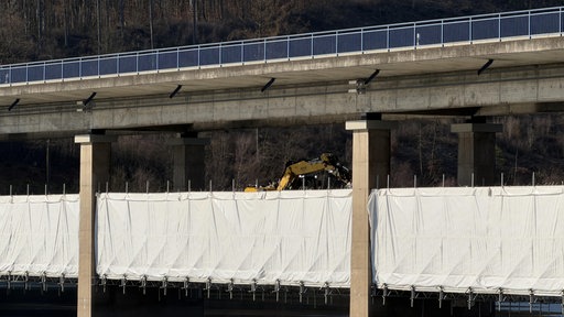 Ein Bagger auf einer Doppelstockbrücke, die saniert wird.