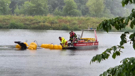 Einsatzkräfte in einem Boot ziehen etwas aus dem Wasser