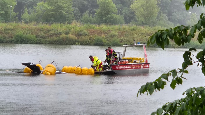 Einsatzkräfte in einem Boot ziehen etwas aus dem Wasser