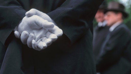 Sargträger und Hände mit weissen Handschuhen.