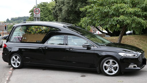 Ein schwarzer Leichenwagen auf einer Straße.