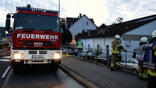 Die Feuerwehr steht neben dem Gebäude bei dem die Autos gebrannt haben 