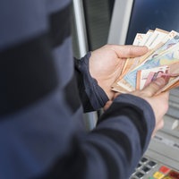 Eine Person hält mehrere Geldscheine in der Hand, die zuvor in einem manipulierten Automaten stecken geblieben sind.
