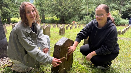 Schülerinnen aus Marsberg säubern Grabsteine auf dem alten Friedhof.  