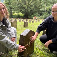 Schülerinnen aus Marsberg säubern Grabsteine auf dem alten Friedhof.  