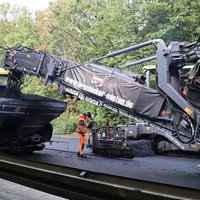 Baufahrzeuge auf einer Straße, die den Asphalt erneuern.