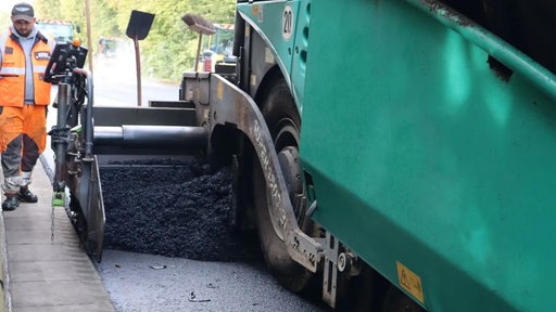 Ein Baufahrzeug auf einer Straße, das den Asphalt erneuert.