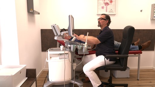 Ein Mann schaut auf einen Computer in einem Patientenzimmer