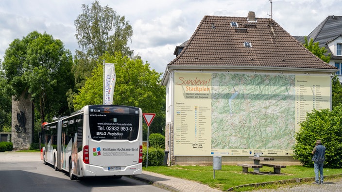 Eine Wanderkarte von Sundern, dem Sorpesee und der Umgebung in Übergröße auf einer Hauswand und ein Linienbus
