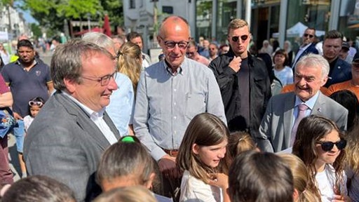 Bundeskanzler Friedrich Merz gemeinsam mit Herbert Reul und Oliver Krischer und einer Kindergruppe