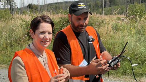 NRW-Landwirtschaftsministerin Silke Gorißen steht neben einem Forstarbeiter, der eine Drohne steuert