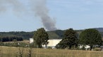 Dunkler Rauch zieht über einem Wald auf.