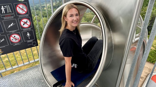 Ein Mädchen sitzt in einer Rutsche.
