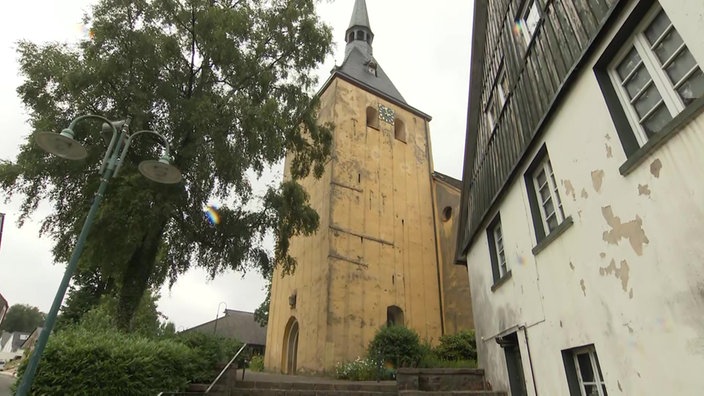 Eine gelbe Kirche neben einem weißen Haus.