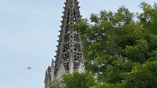 Eine Drohne fliegt neben einem Kirchturm