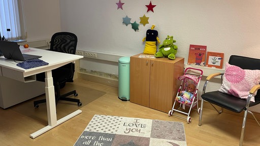 Ein Zimmer mit einem Schreibtisch, Sitzmöglichkeiten und Spielsachen.