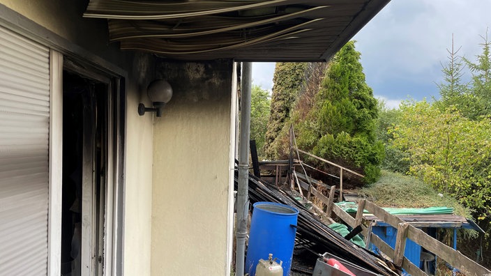 Verbranntes Holz liegt neben einem Haus welches gebrannt hat 