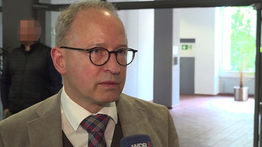 Der Rechtsanwalt des Angeklagten schaut in die Kamera und spricht in ein WDR-Mikrofon