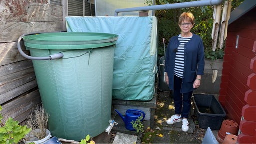 Gabriele Stähler steht neben einer grünen Regentonne.