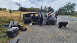 Ein zerstörter Kleintransporter auf einer Kiesfläche am Rande einer Straße