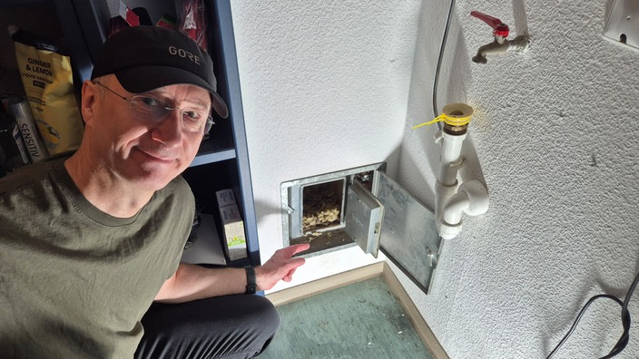 Marco Berg Hausbesitzer und Finder der Tiere zeigt auf eine Kaminklappe