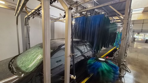 Ein Auto fährt durch eine Waschstraße und wird gewaschen
