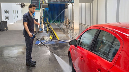 Ein Mitarbeiter reinigt ein Auto in einer Waschanlage