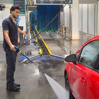 Ein Mitarbeiter reinigt ein Auto in einer Waschanlage