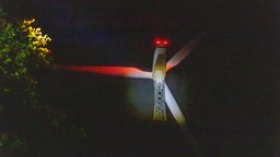 Windrad wird bei Nacht angeleuchtet