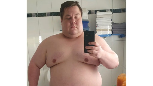 Ein Mann der ein Spiegelbild macht und oberkörperfrei ist.