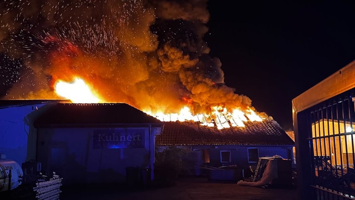 Eine Lagerhalle steht in Flammen.