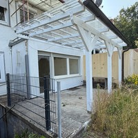 Ein Haus mit Garten und kleiner Überdachung.